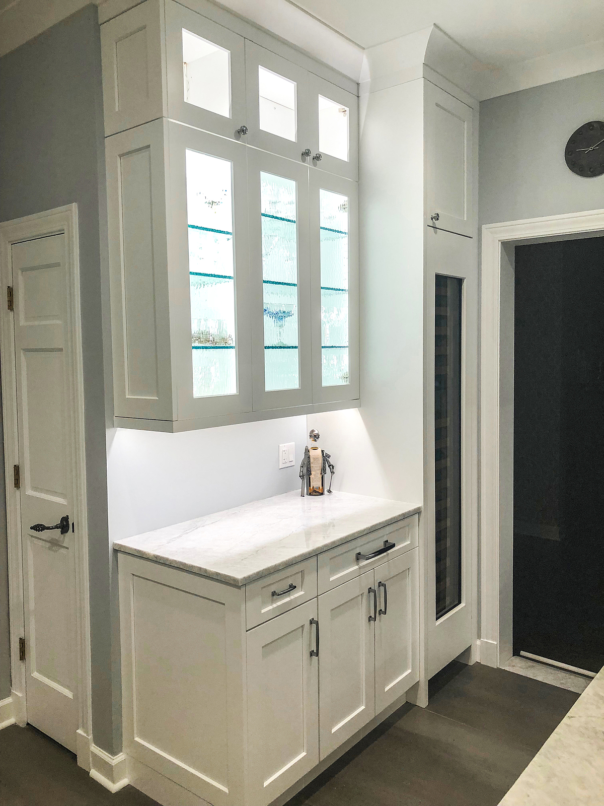 Closeup of a white wall cabinet with shelving and glass doors. 